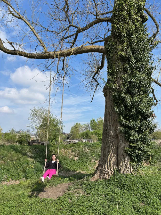 Eveline op een schommel onder een grote boom