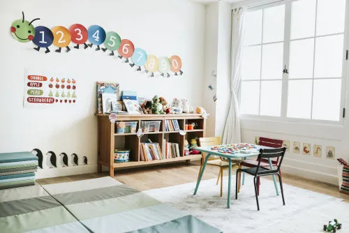 Een kleurrijk klaslokaal met boekenkast en speeltafel