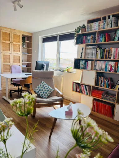 De praktijkruimte met een boekenkast, een zetel en een bureau
